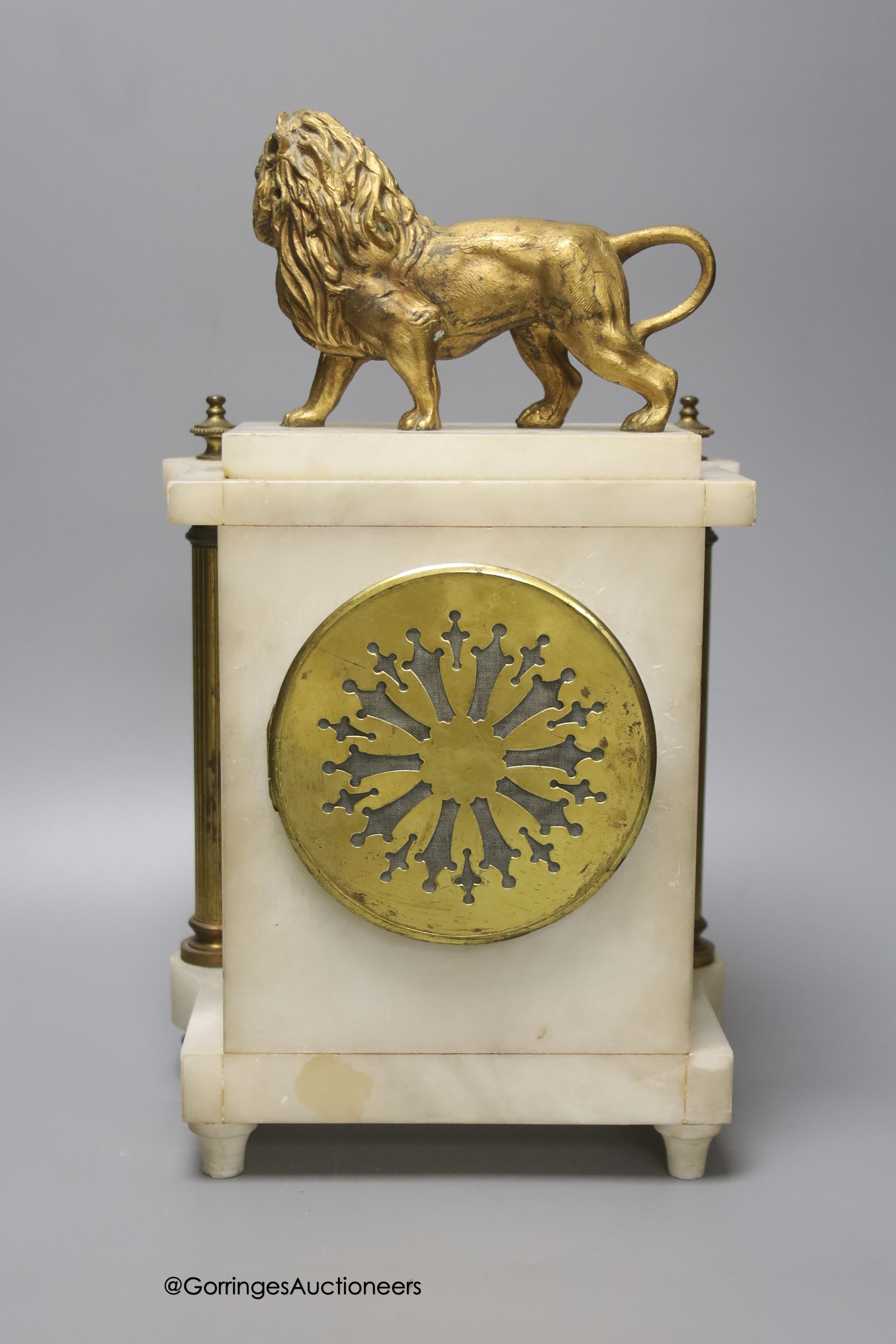 A Victorian alabaster mantel clock, with gilt metal lion surmount, French skeleton movement with pendulum, 34cm